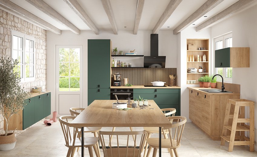 Cuisine ouverte style campagne avec façades vertes, poutres apparentes et grande table en bois.