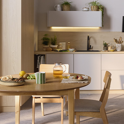 Cuisine lumineuse contemporaine avec table ronde en bois et buffets clairs, petit-déjeuner servi sur la table